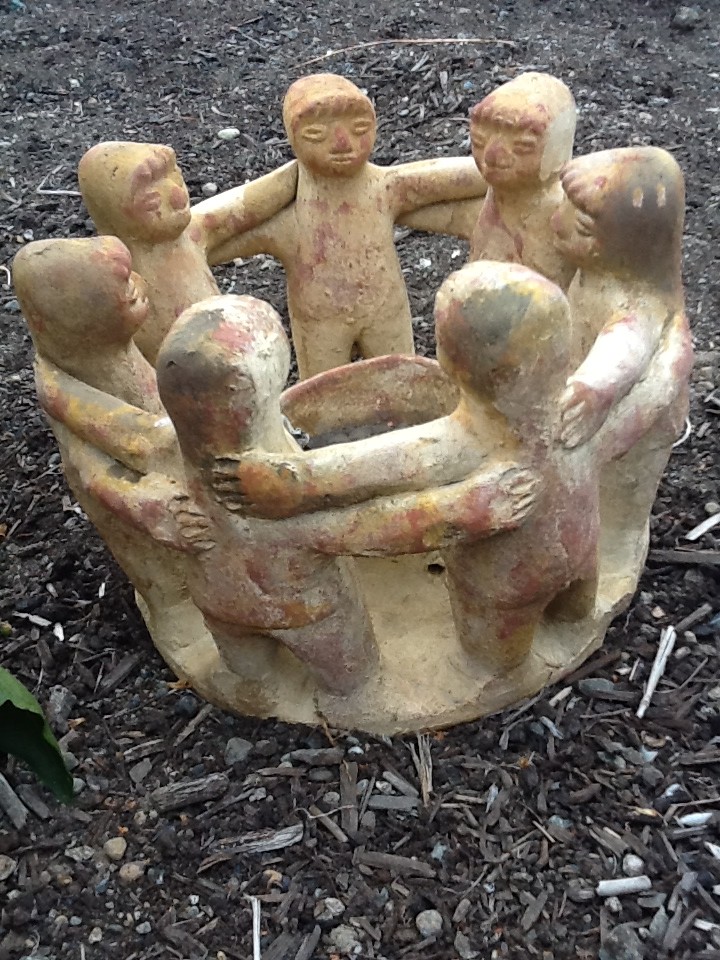 Reddish ceramic of seven people with linked arms standing in a circle